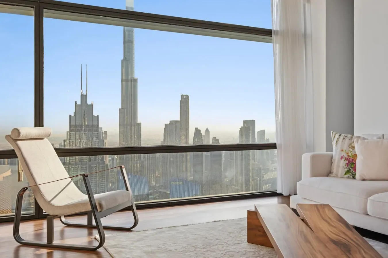 Una sala luminosa con una butaca y el horizonte urbano visible por la ventana.
