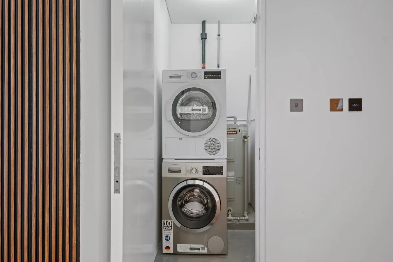 A laundry area with a stacked washer and dryer in a narrow alcove.