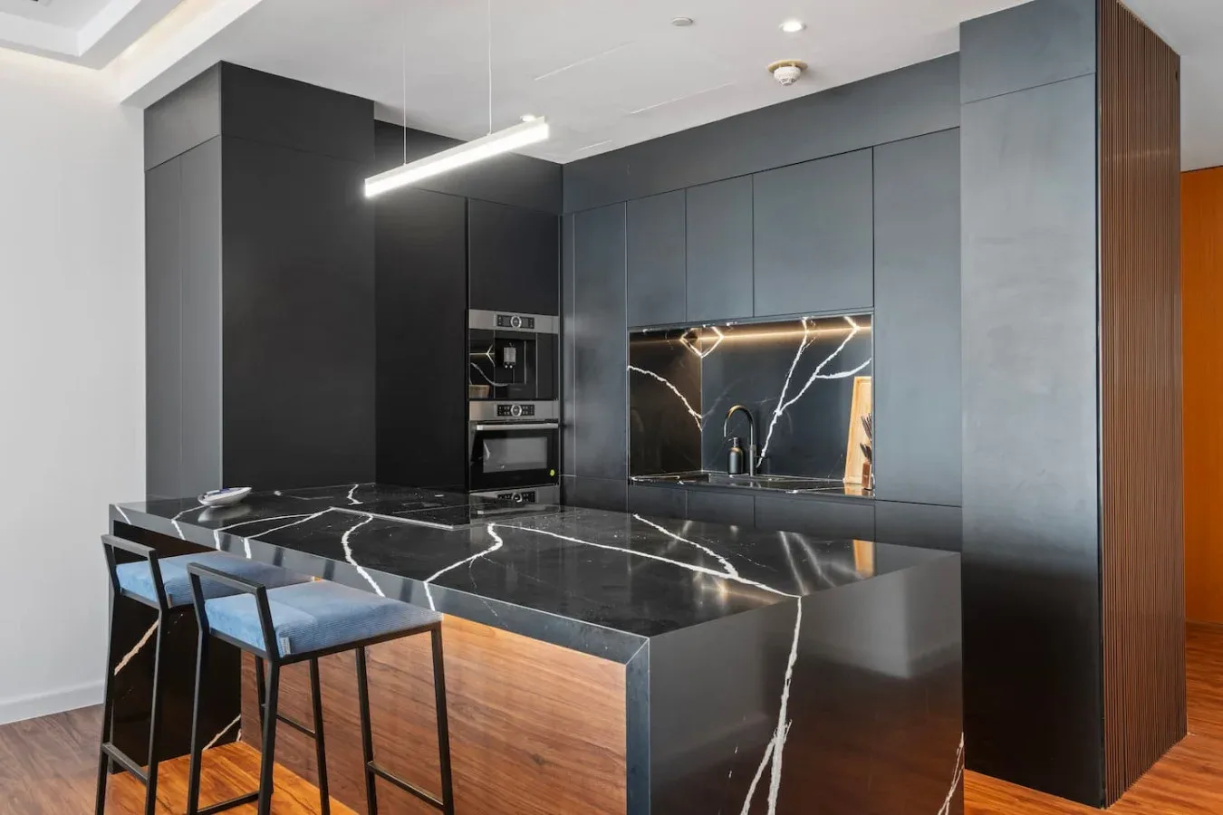 A modern kitchen with dark cabinetry and a marble-patterned island.