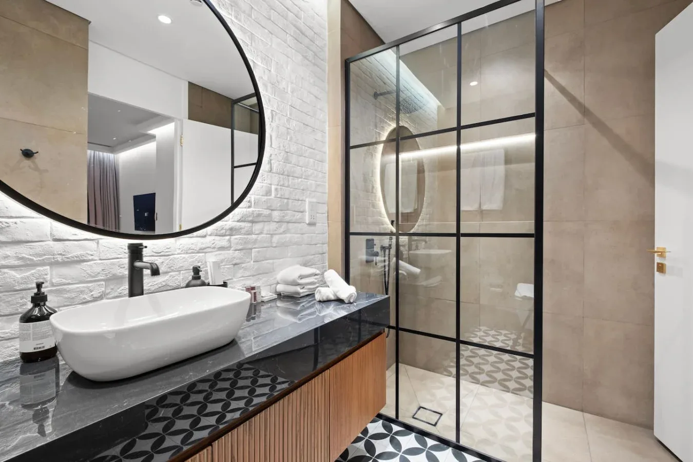 A modern bathroom with a vessel sink, dark countertop, and glass shower.