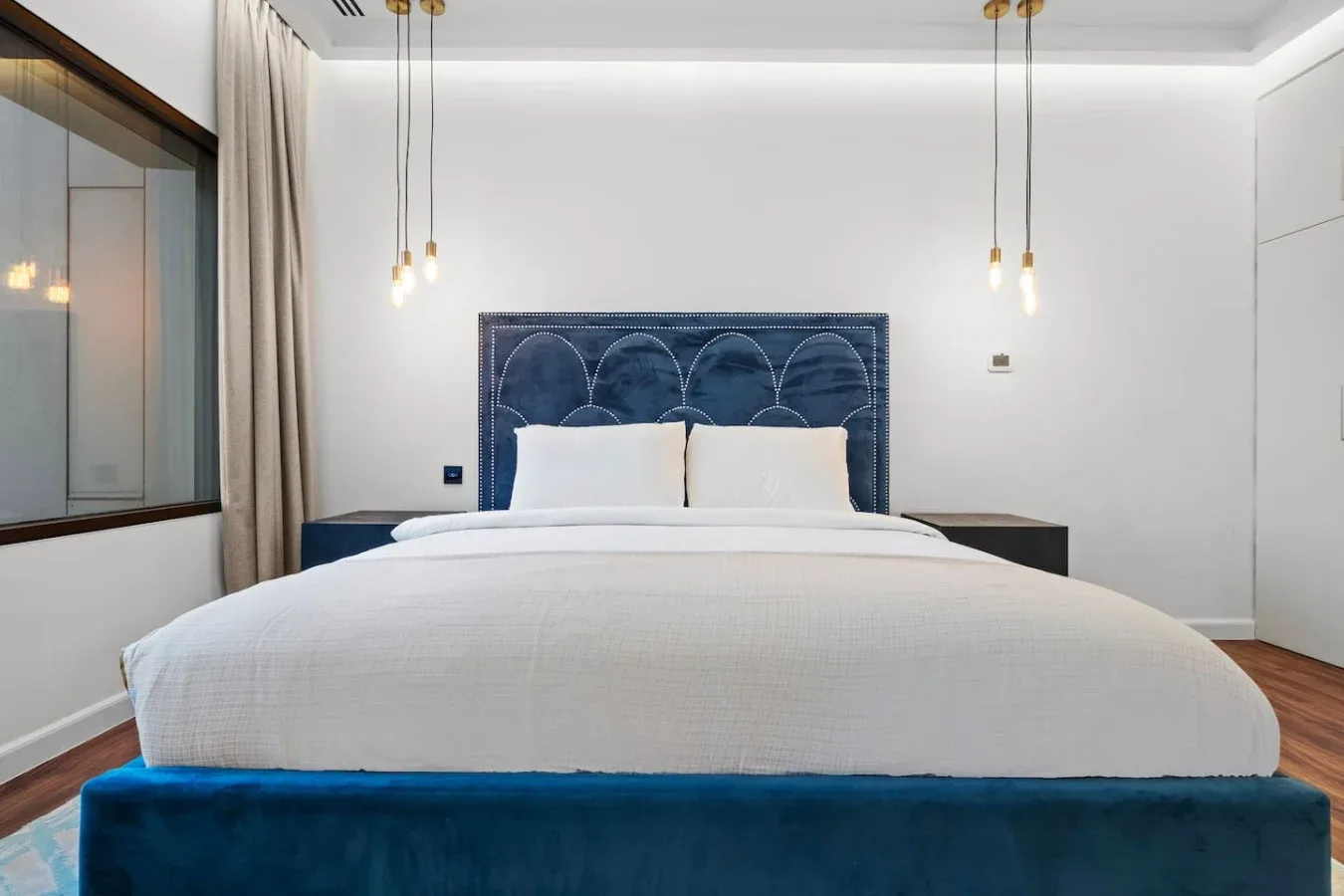 A bedroom with a neatly made bed and a dark upholstered headboard.