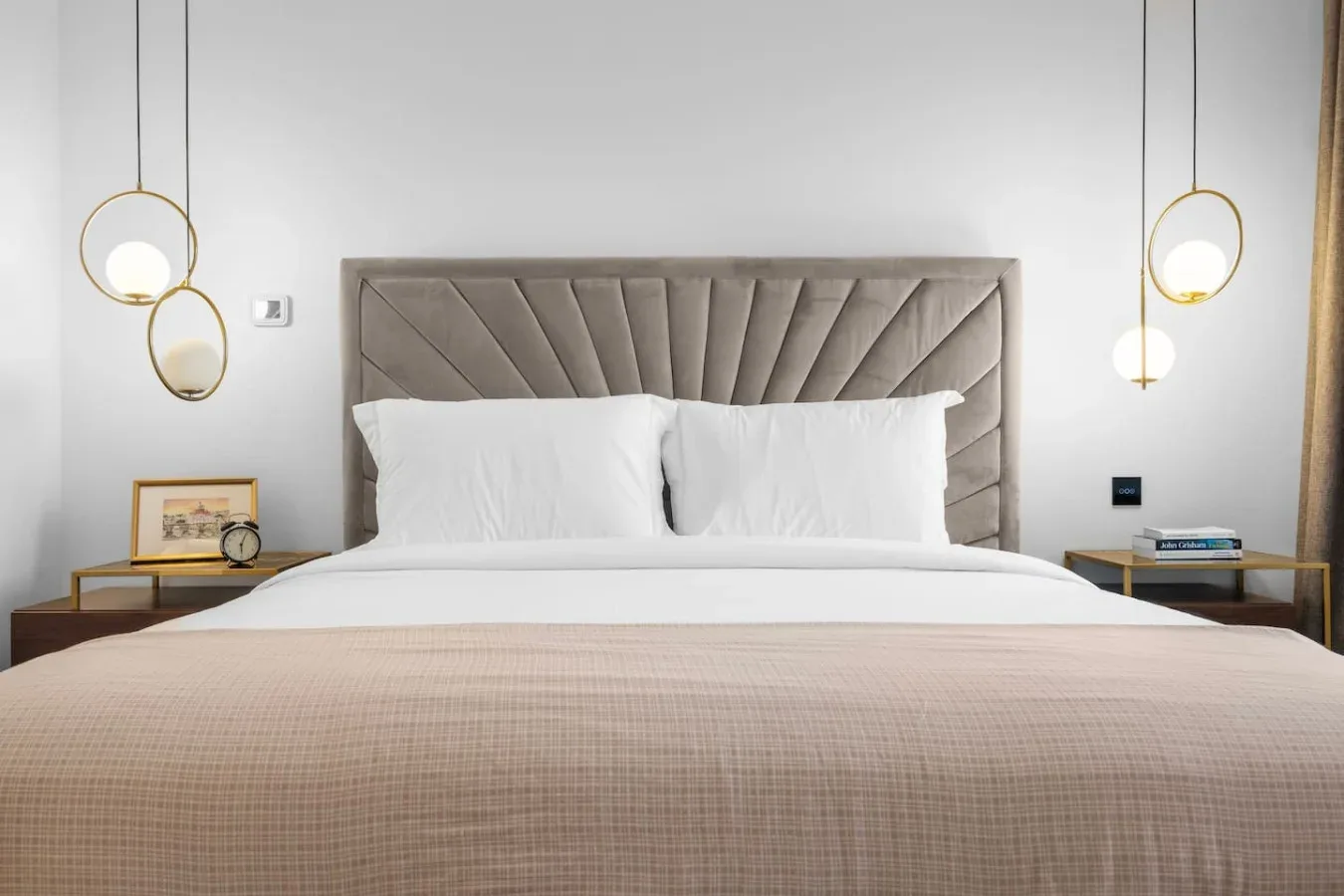 A bedroom with a neatly made bed and padded headboard.