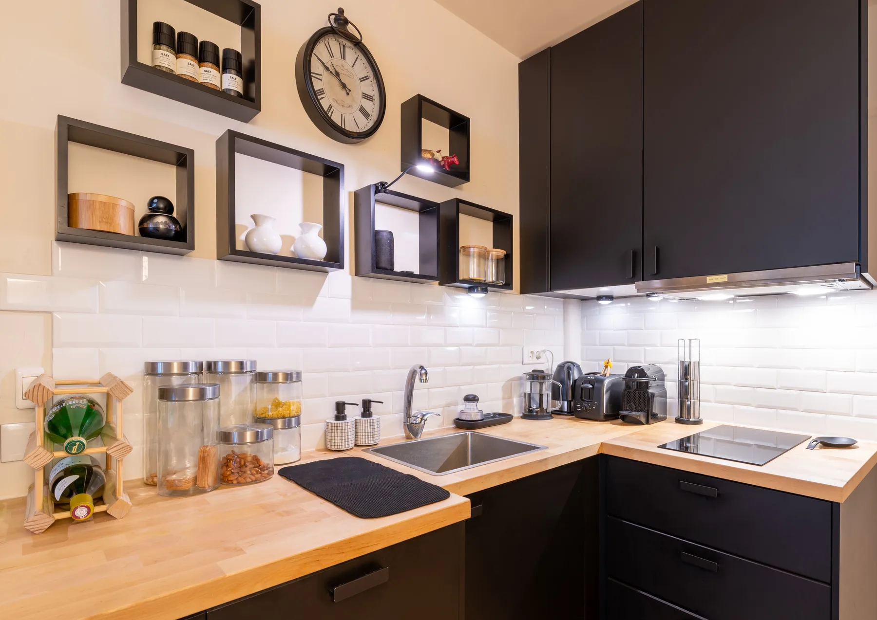 Una cocina moderna con gabinetes oscuros, encimeras de madera y un fregadero doble.