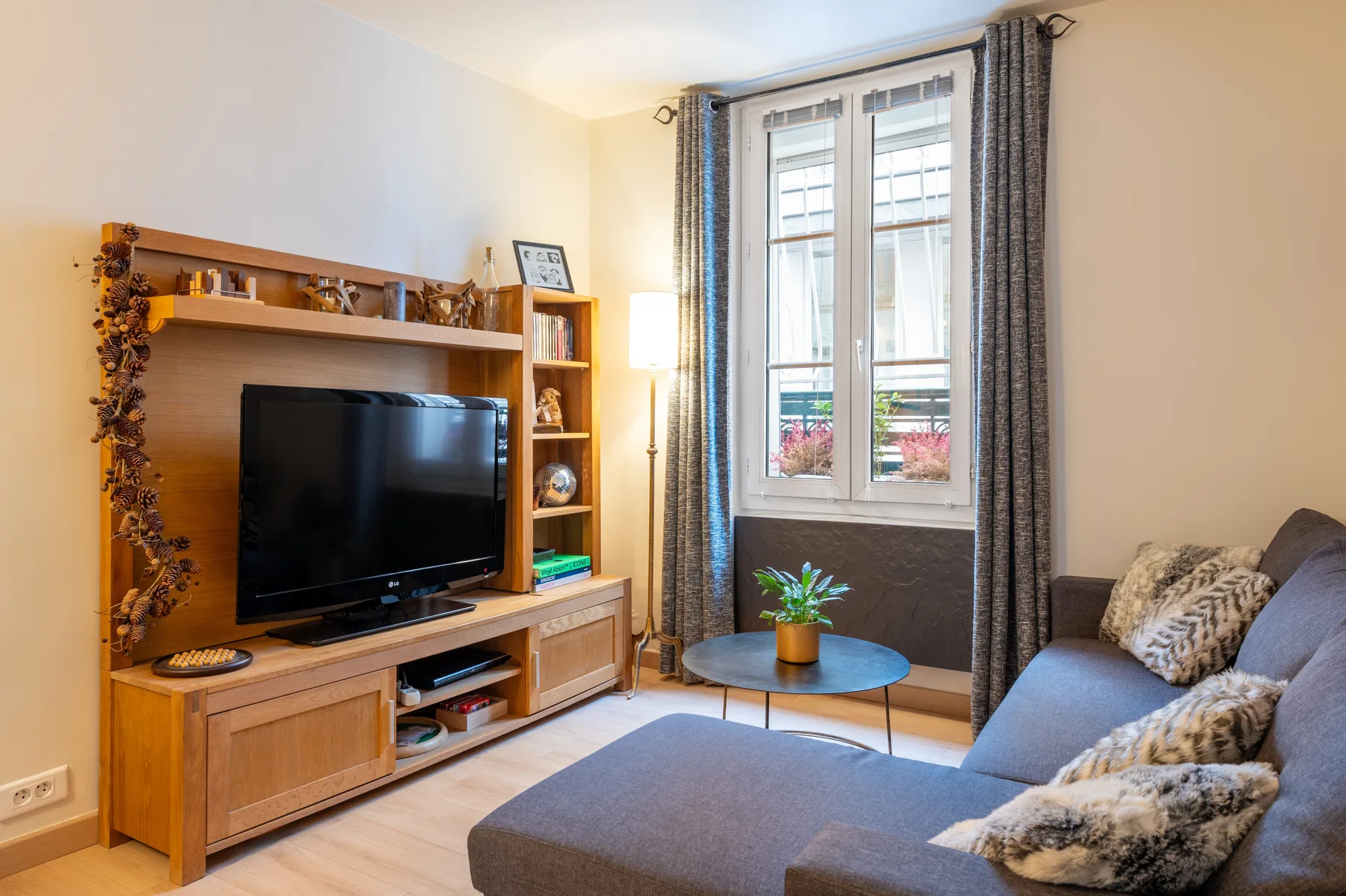 A living room with a television, seating, and a tall window.