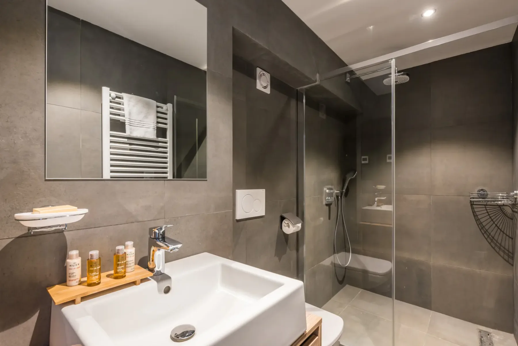 A bathroom with a sink, wall mirror, and glass shower enclosure.