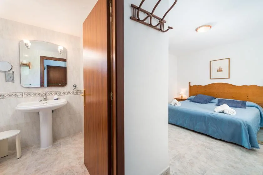 A bedroom with blue bedding is visible beside a bathroom with a sink.