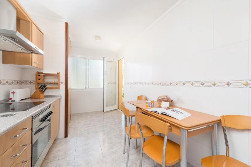 A kitchen and dining area with a table and orange seating.