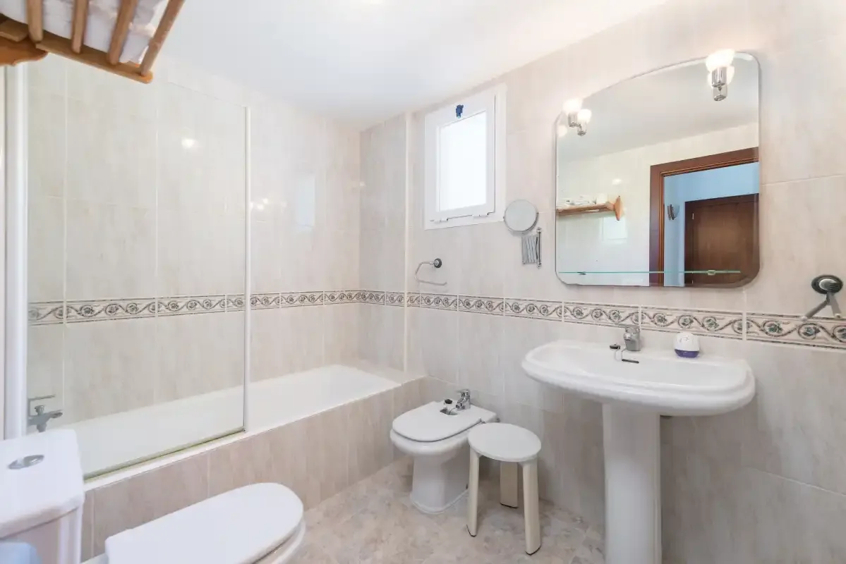 A tiled bathroom with a bathtub, sink, and mirror.