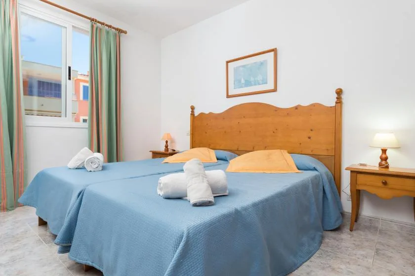 A bedroom with a large bed covered in blue bedding and a wooden headboard.