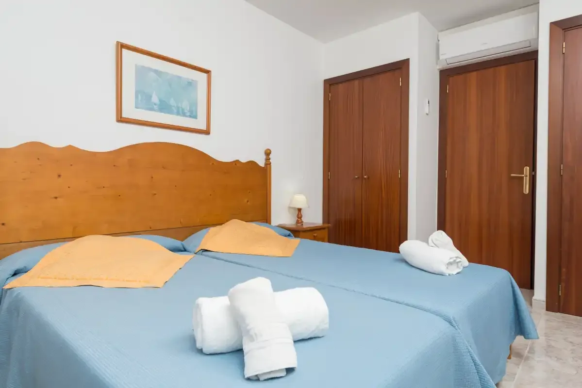 A bedroom with blue bedding and a wooden headboard.