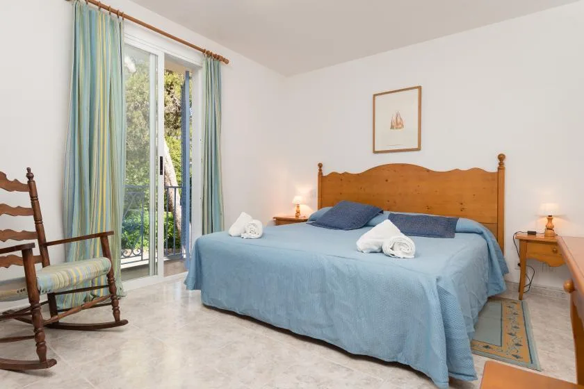 A bedroom with a bed, bedside tables, and a glass door opening to greenery.