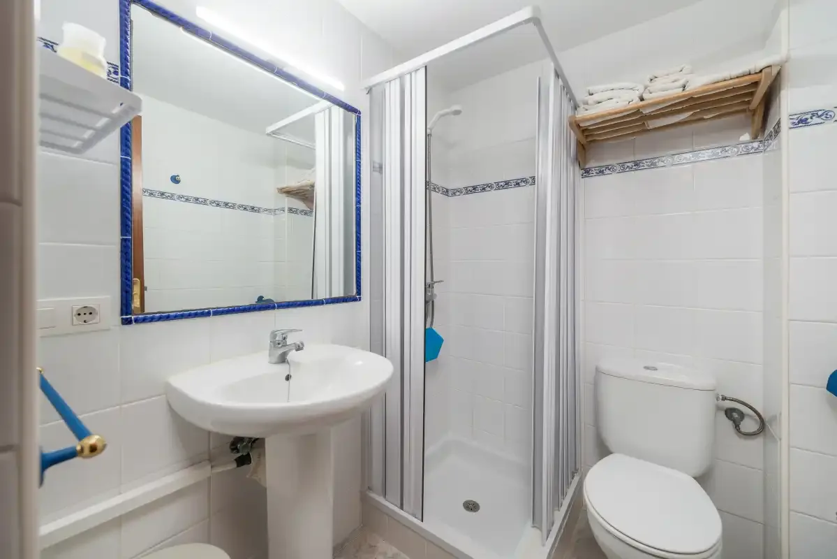 A tiled bathroom with a sink, mirror, shower, and toilet.