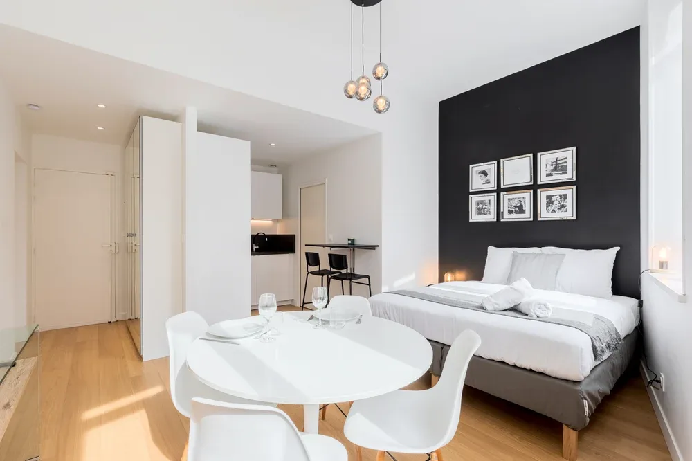 Dormitorio con cama, mesa de comedor y zona de cocina.