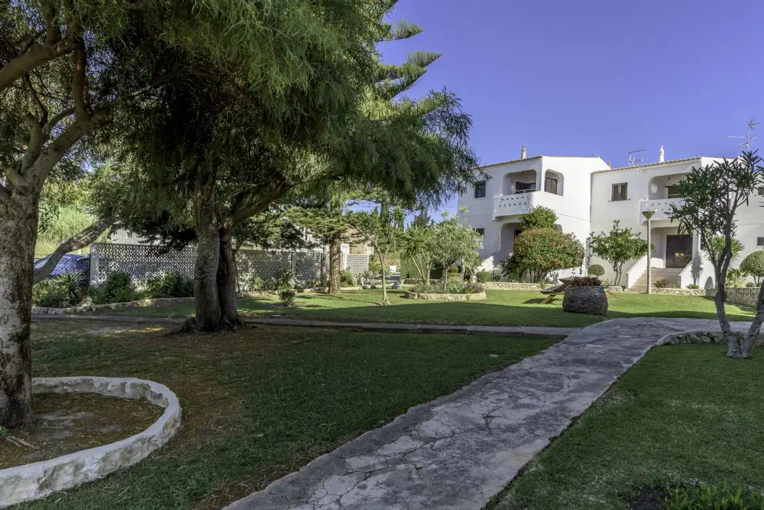 Un jardín ajardinado con un camino de piedra conduce hacia un edificio blanco.