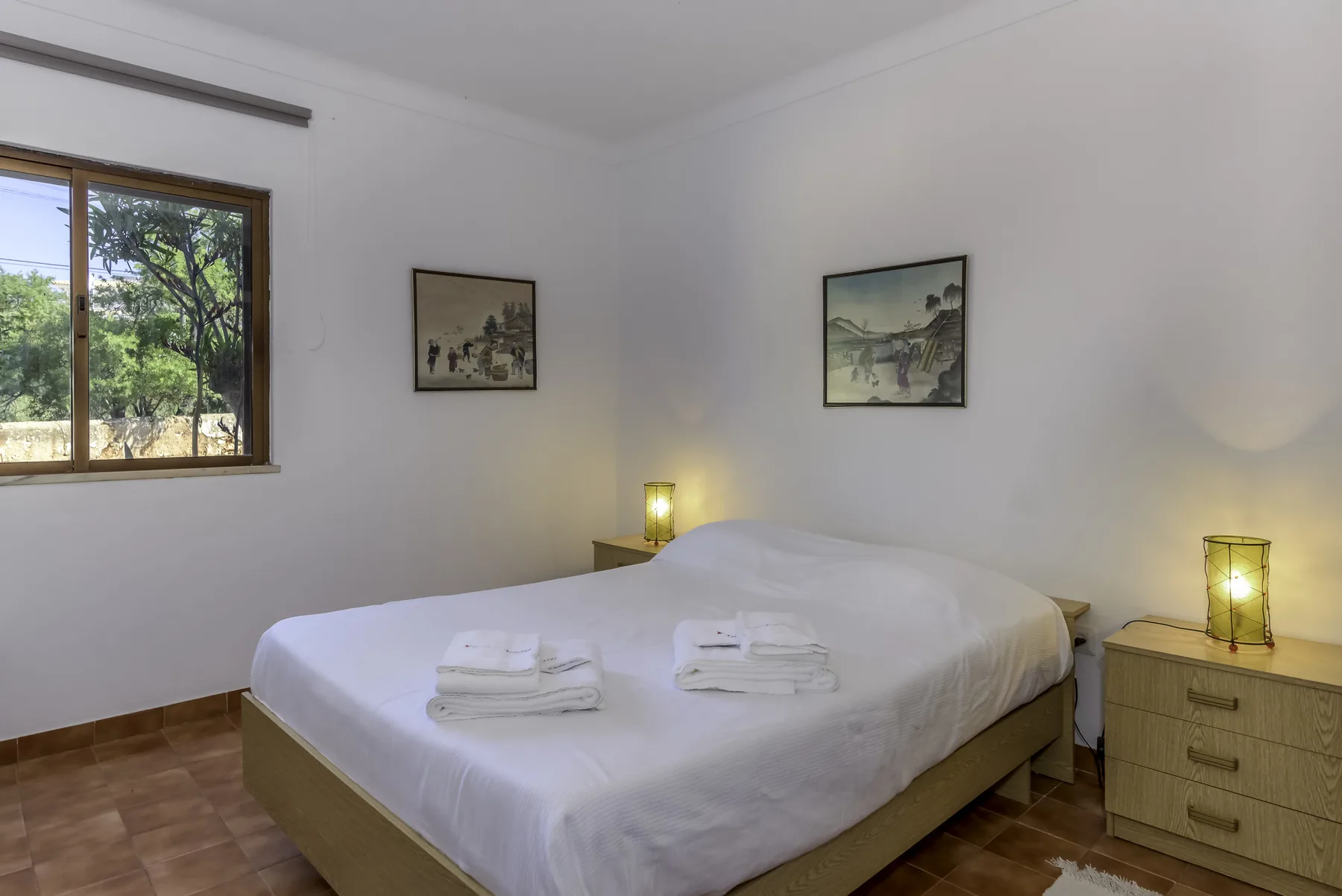 Un dormitorio con una cama doble, toallas dobladas y mesitas de noche.