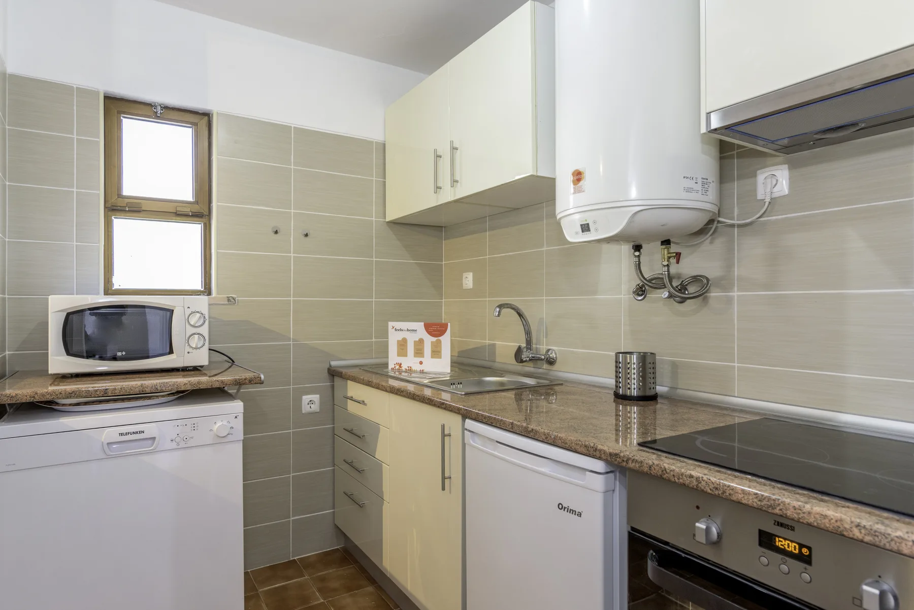 A compact kitchen with a microwave, sink, and built-in cooktop.