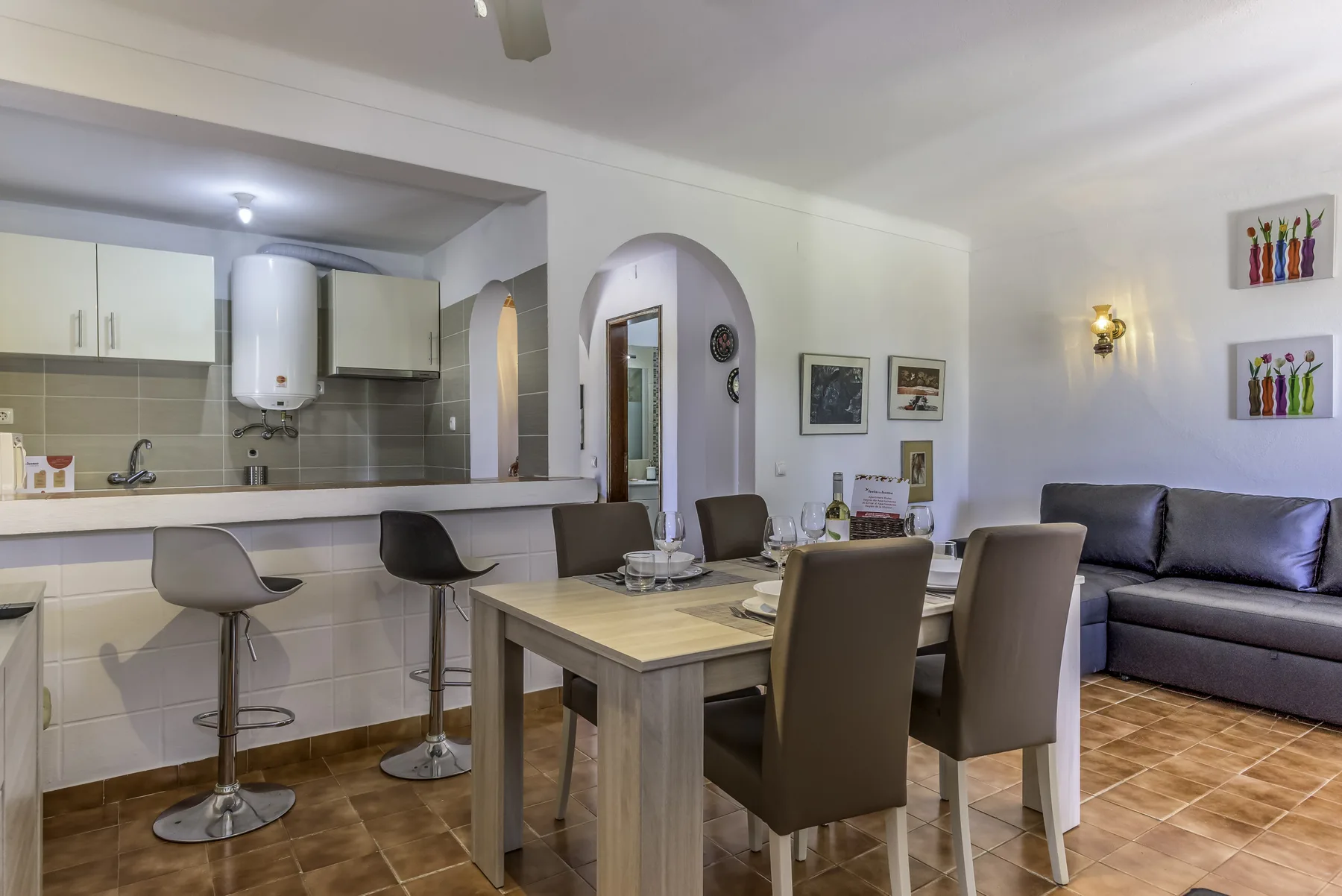 A dining area with a table and chairs beside an open kitchen and living space.