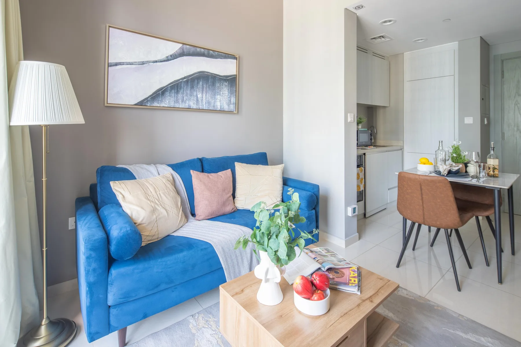 Sala de estar con un sofá azul junto a una zona de comedor.