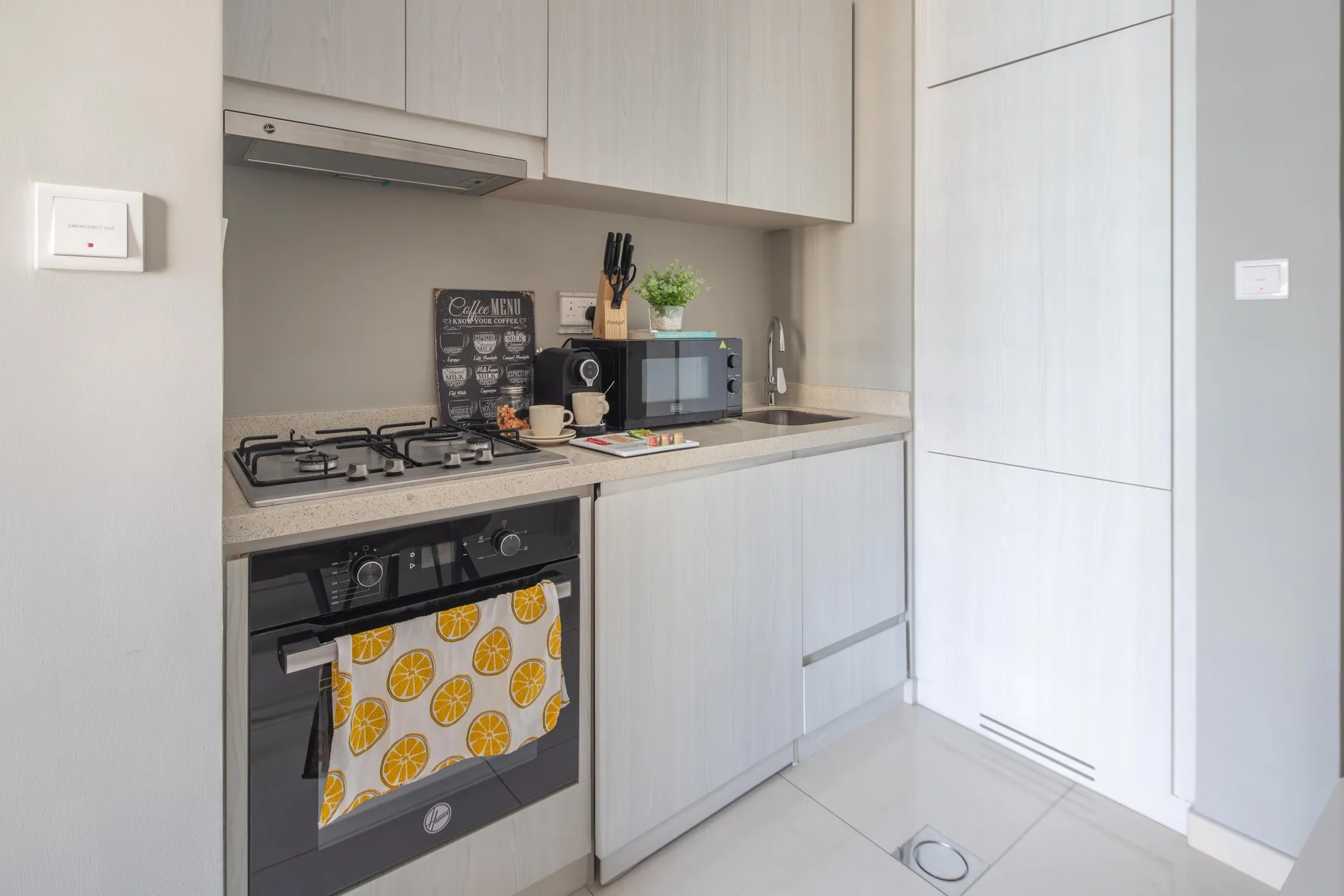 Una cocina compacta con gabinetes claros, una estufa y electrodomésticos sobre la encimera.