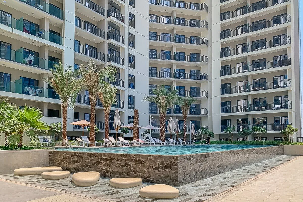 Una piscina exterior se encuentra en un patio rodeado por un edificio de varios pisos.