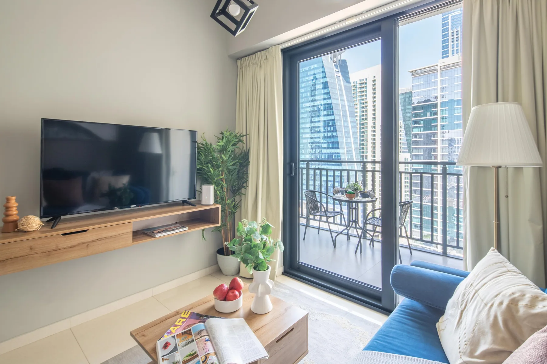 Una sala de estar con televisor, asientos y puertas de vidrio que dan a un balcón.