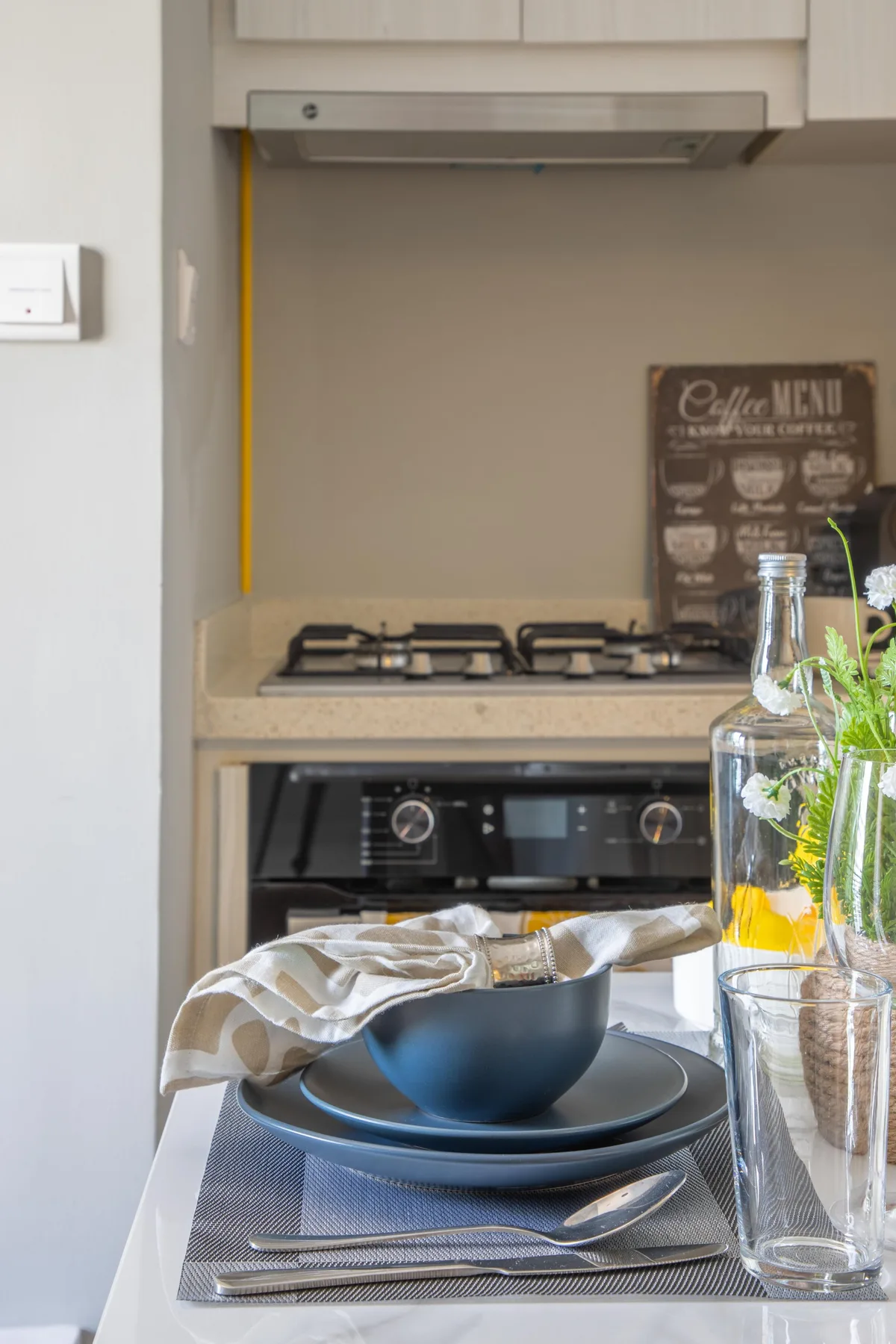 Una encimera de cocina con una estufa y una mesa puesta en primer plano.