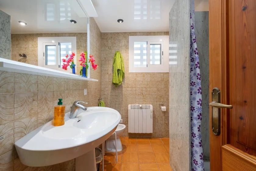 Un baño con azulejos, lavabo, espejo y cortina de ducha.