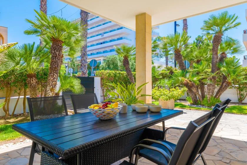 Comedor exterior cubierto con una mesa y sillas entre palmeras.