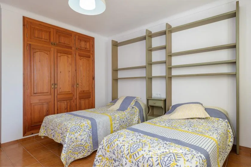Un dormitorio con dos camas y estanterías empotradas a lo largo de la pared.