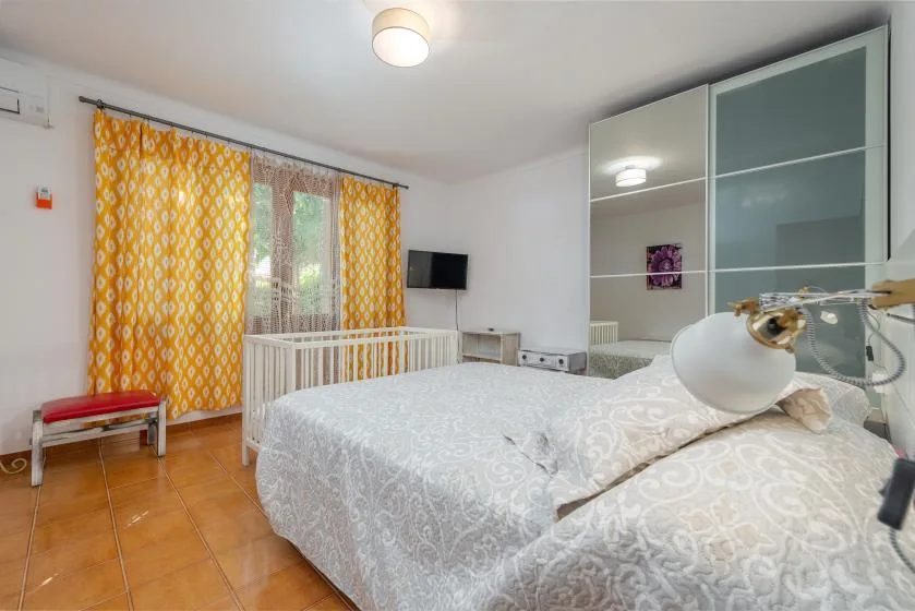 Un dormitorio con una cama, cortinas estampadas y un armario con puertas de cristal.