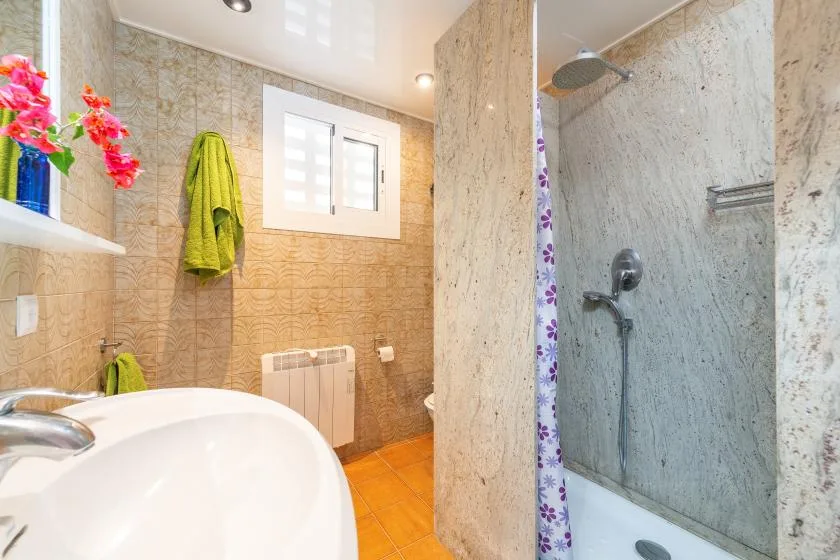 Un baño alicatado con un lavabo y una zona de ducha abierta.
