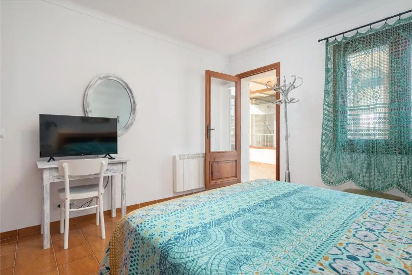 Un dormitorio con una colcha estampada, un televisor y una puerta abierta.