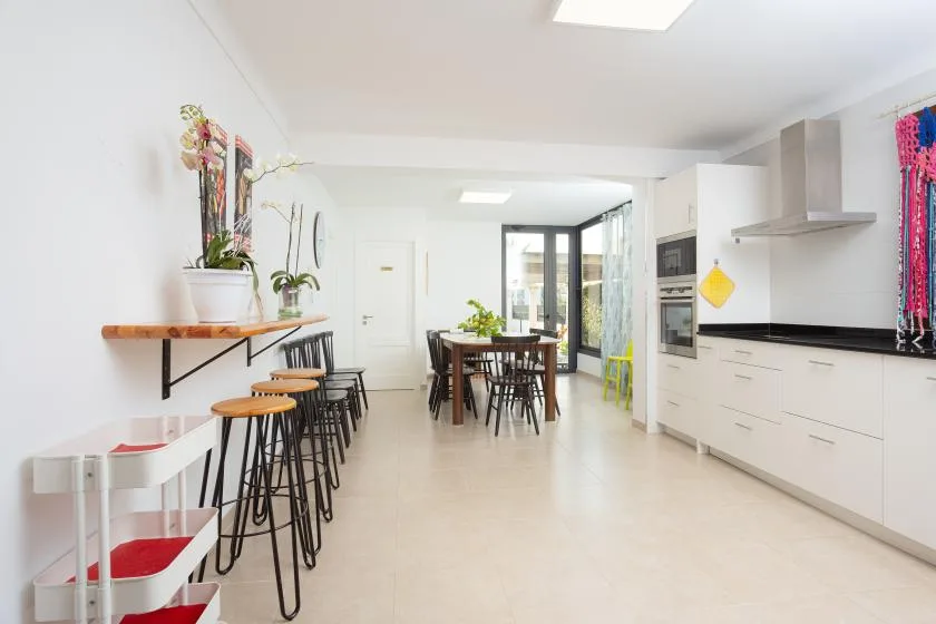 Una cocina luminosa con comedor, una barra larga y una mesa.