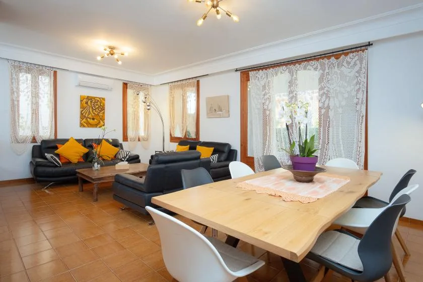 Una zona de estar y comedor con asientos oscuros y una mesa de madera.