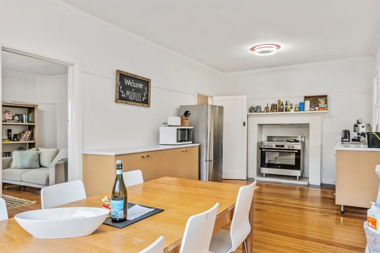 A kitchen and dining area with a wooden table and appliances.
