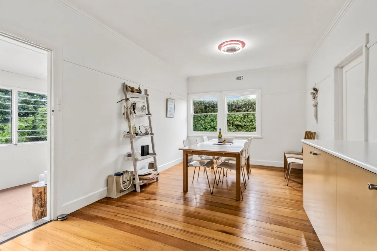 A bright dining area with a wooden table and large windows.