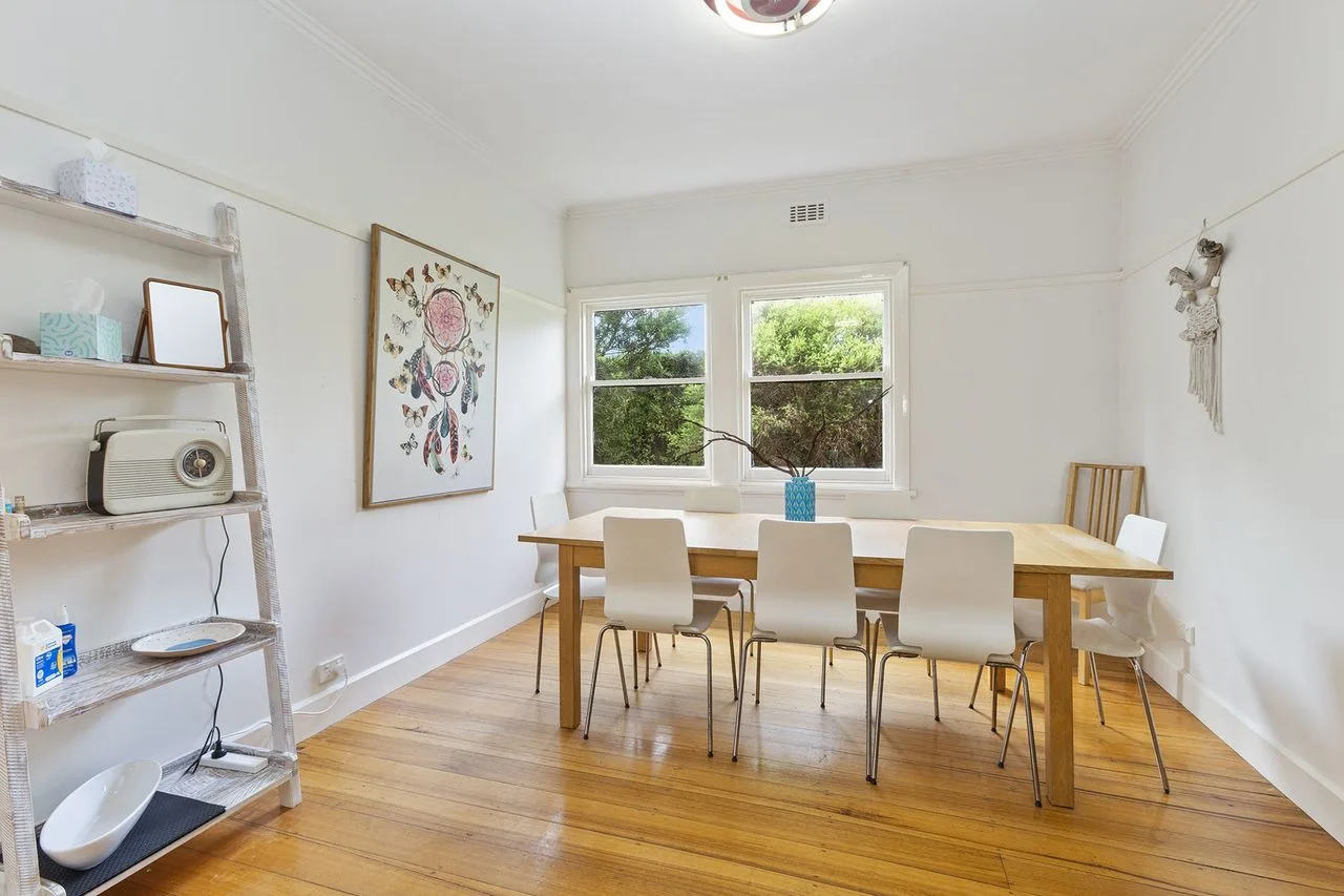 A bright dining area with a table and seating beside a large window.