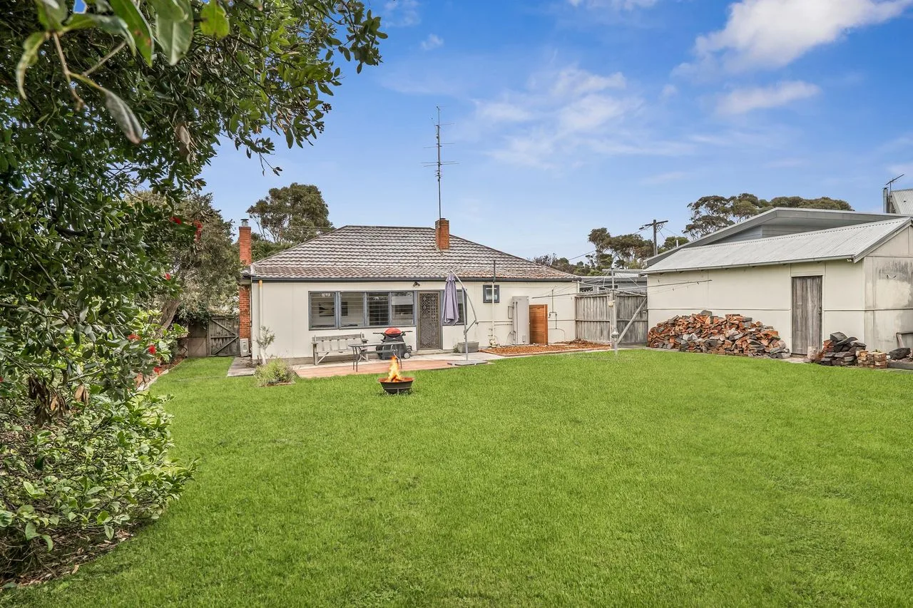 A backyard with a broad lawn, a house, and a detached garage.