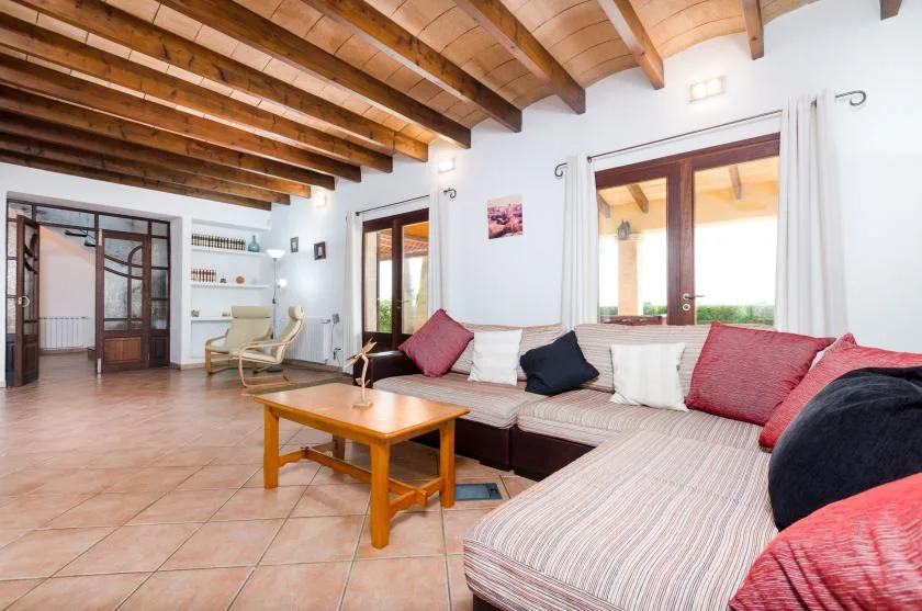 Una sala de estar con asientos en forma de L, mesa de centro de madera y vigas expuestas.