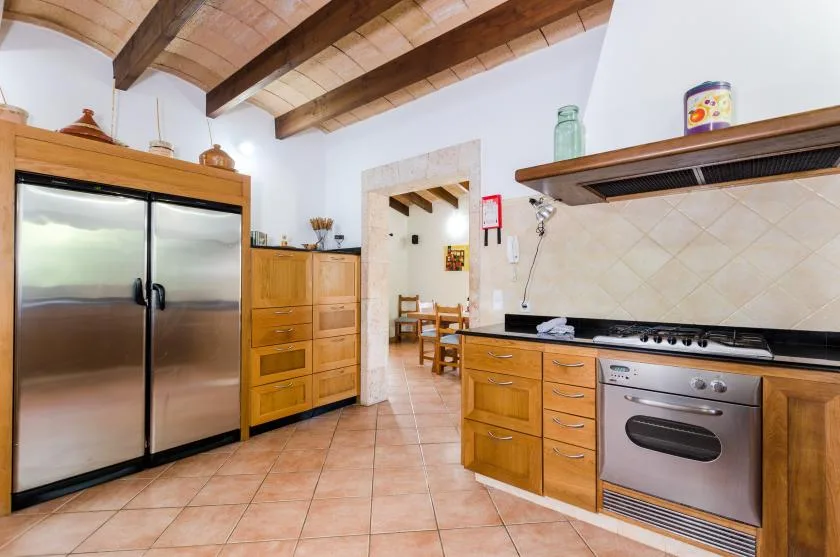 Una cocina con gabinetes de madera, electrodomésticos de acero inoxidable y vigas expuestas en el techo.