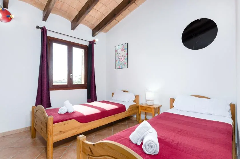Un dormitorio con dos camas, techo de madera y una ventana con cortinas.