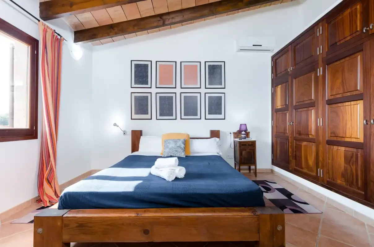 Un dormitorio con una cama, cuadros enmarcados y armarios de madera.
