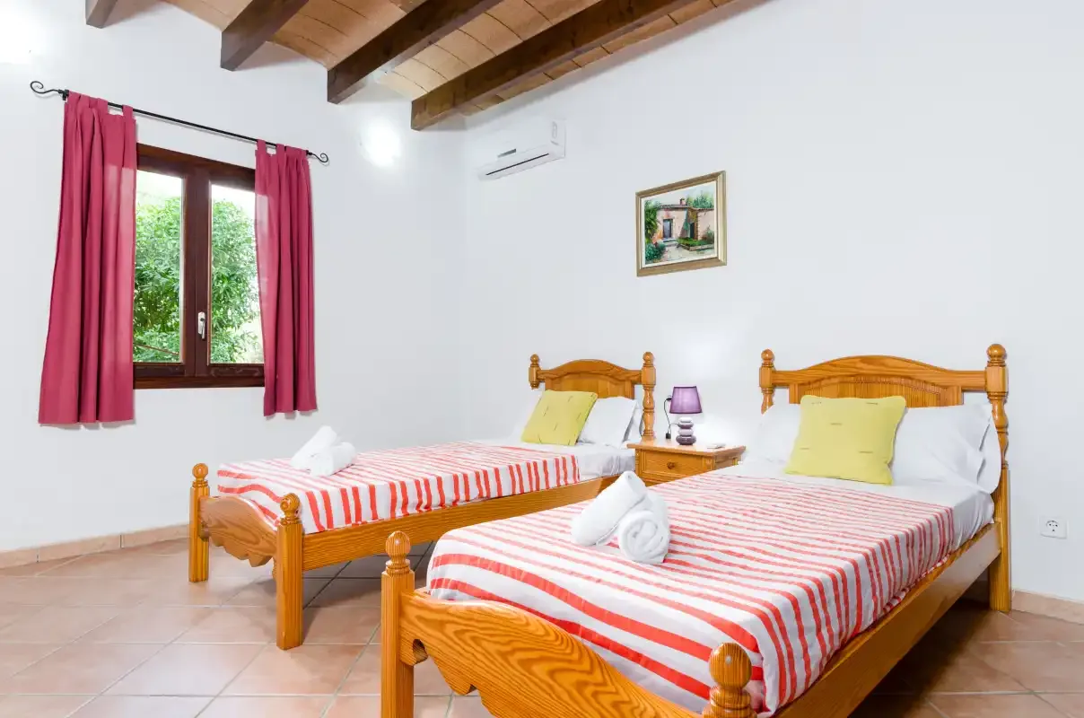 Un dormitorio con dos camas de madera, ropa de cama a rayas y cortinas rosas.