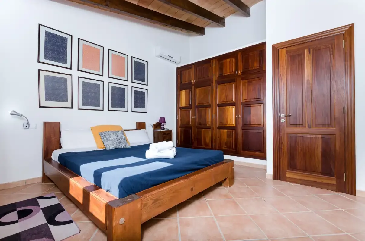 Un dormitorio con una cama de madera y armarios de paneles oscuros.