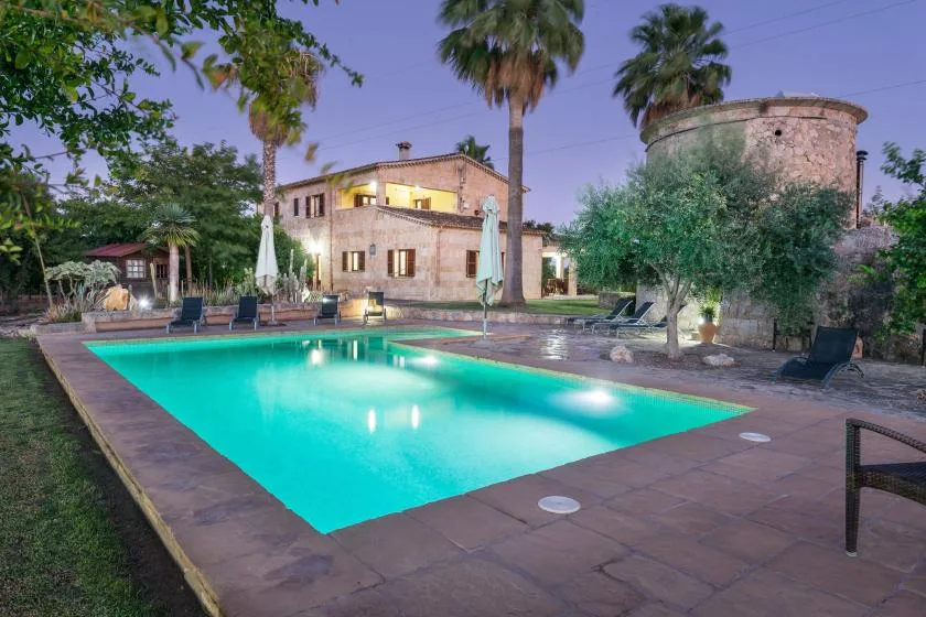 Una piscina al aire libre está junto a un edificio de piedra y palmeras.