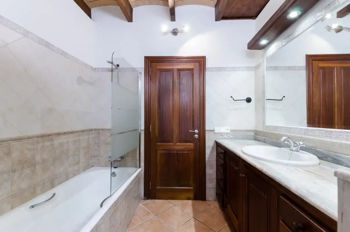 Un baño con bañera, mampara de ducha de vidrio y mueble de lavabo de madera.