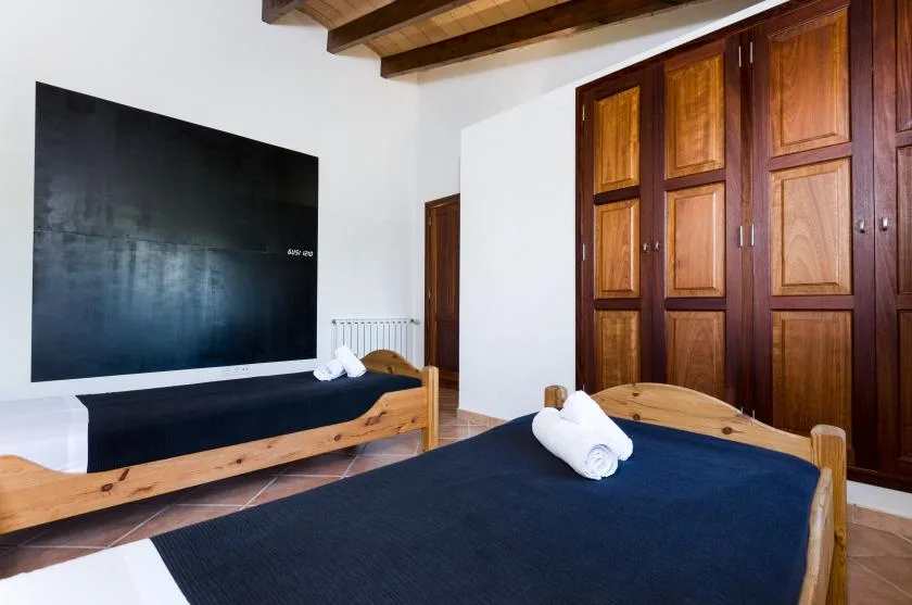 Un dormitorio con dos camas, un televisor en la pared y vigas de madera en el techo.
