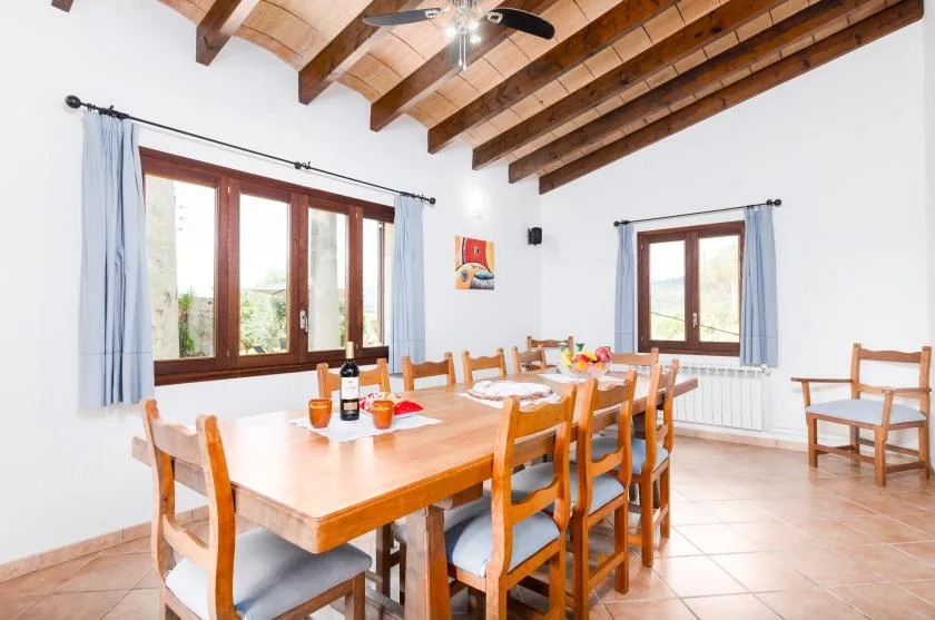 Un comedor con una mesa larga de madera y sillas bajo vigas expuestas.