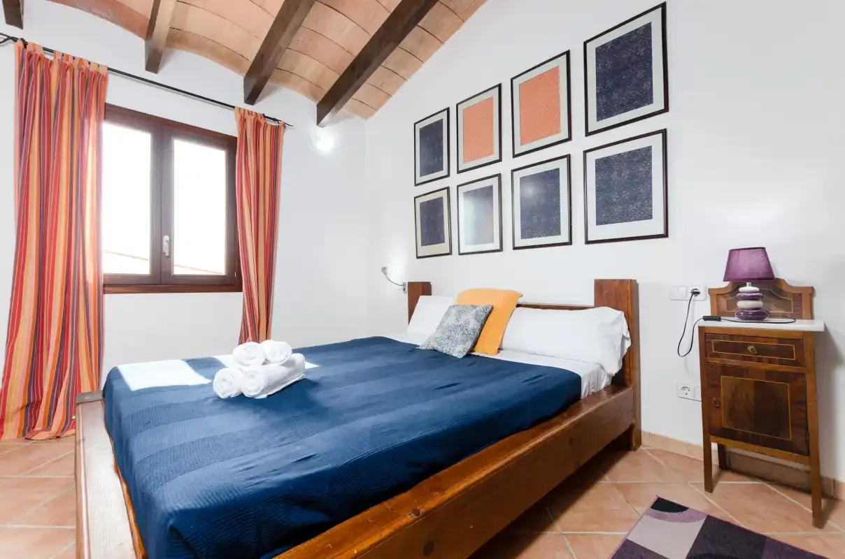 Un dormitorio con una cama de madera, ropa de cama azul y cuadros enmarcados.