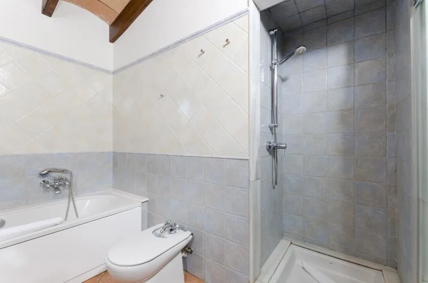 Un baño alicatado con bañera, inodoro y ducha.